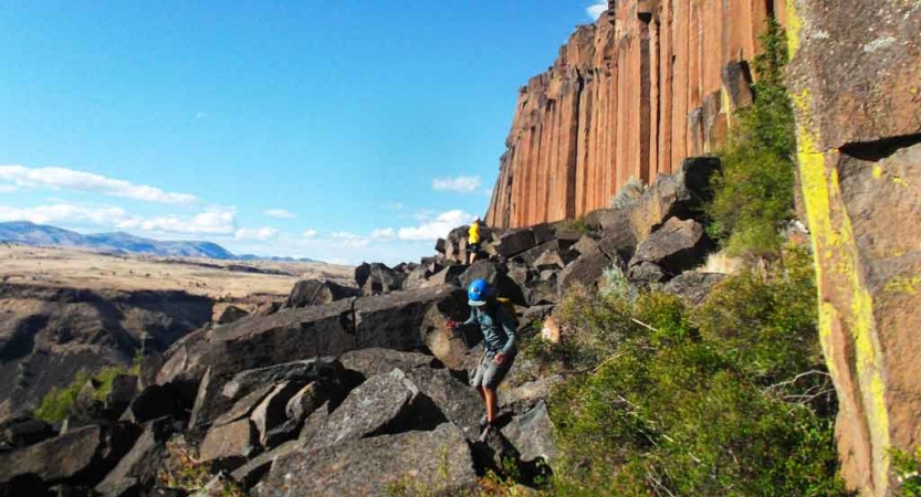 a person wearing a helmet navigates large rocks on an outward bound course